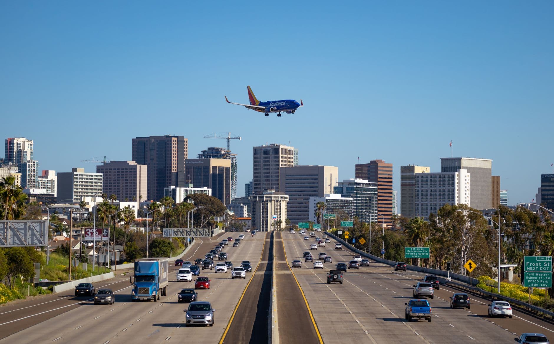 Airplane approaching San Diego airport over busy city freeway and skyline.