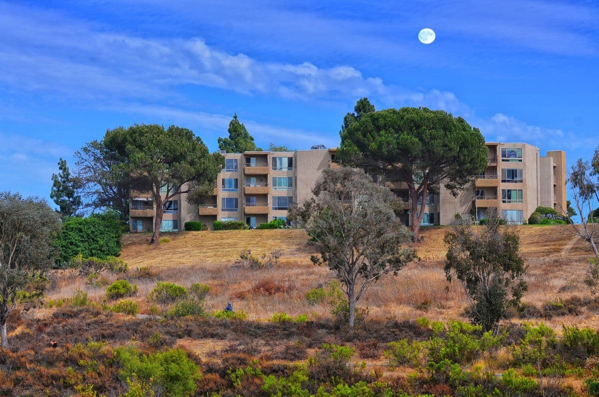 Apartment building surrounded by lush greenery and a clear sky in San Diego.